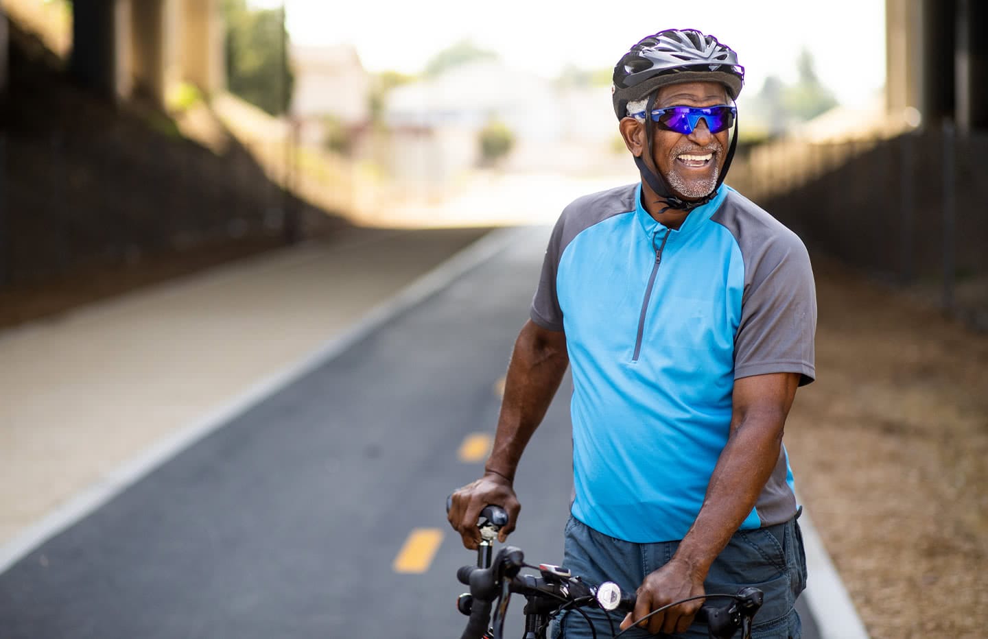 Male on a street standing next to his bicycle smiling