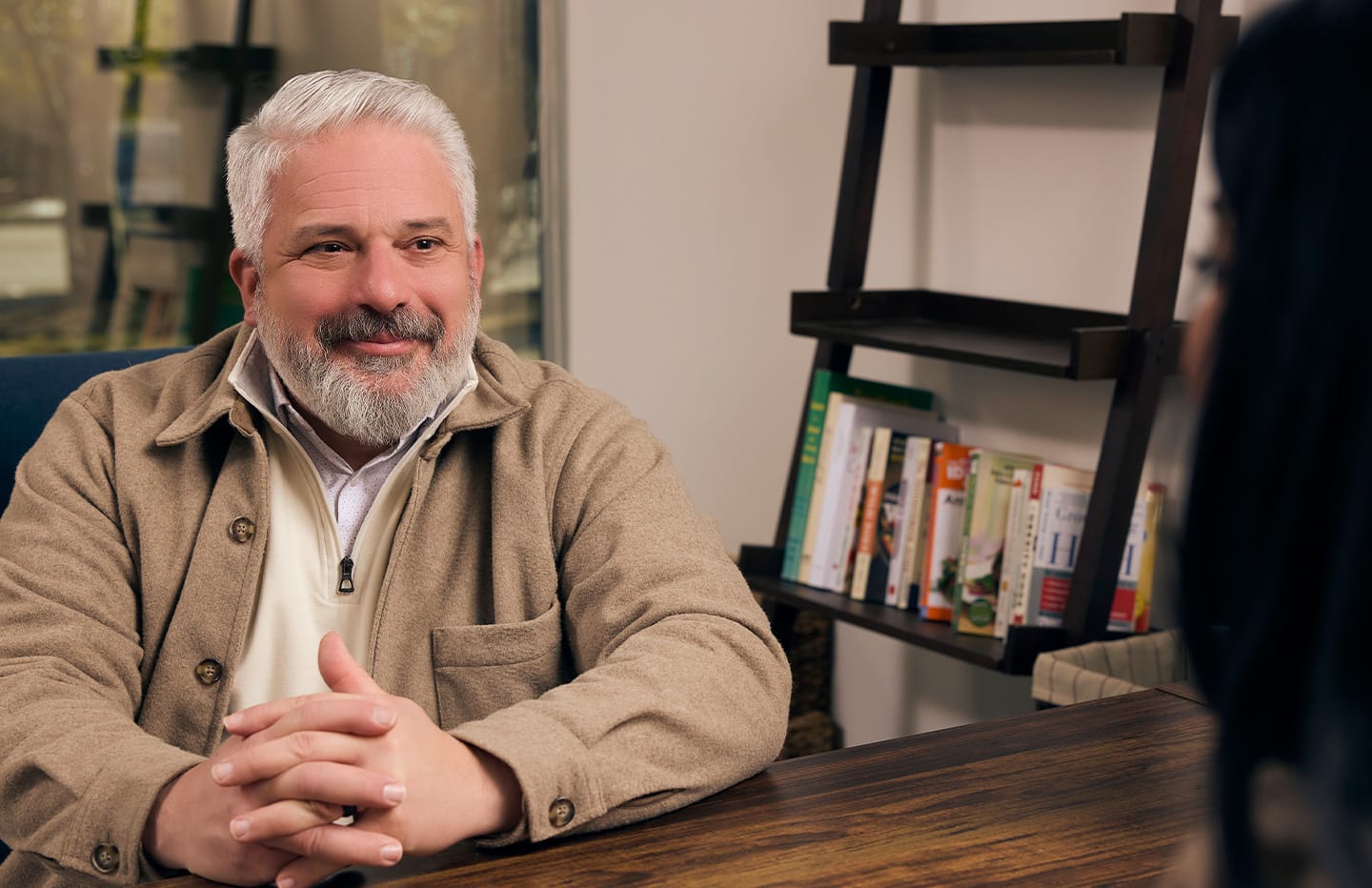 Man smiling at desk across from someone