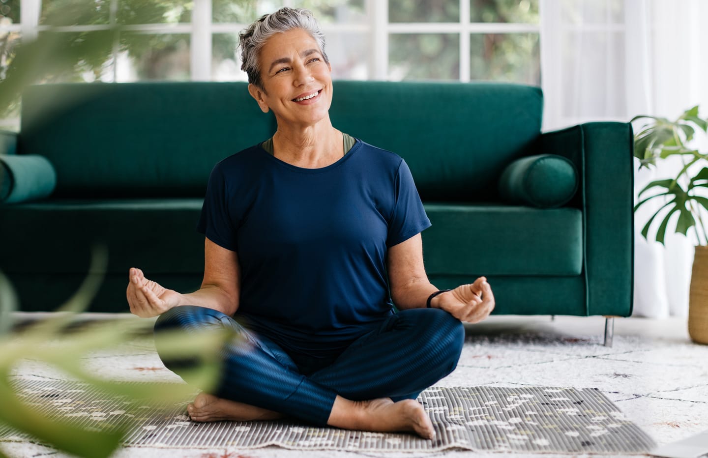 Female sitting on floor in yoga position smiling at the window