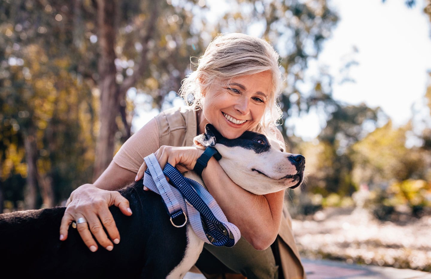Female smiling and hugging her dog outside