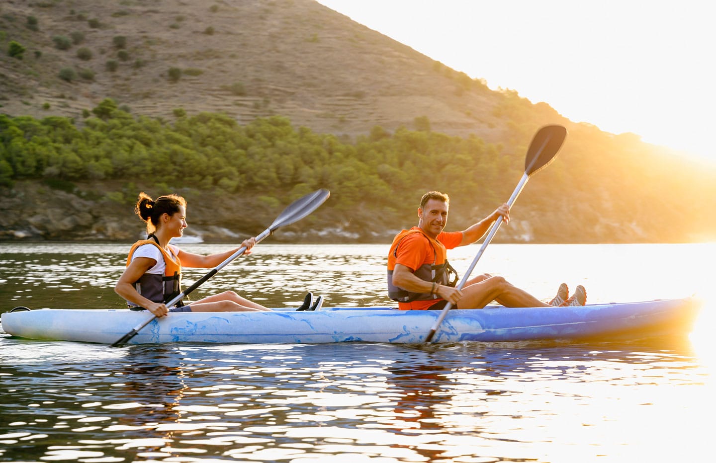 Two individuals sitting in a kayak rowing in the water