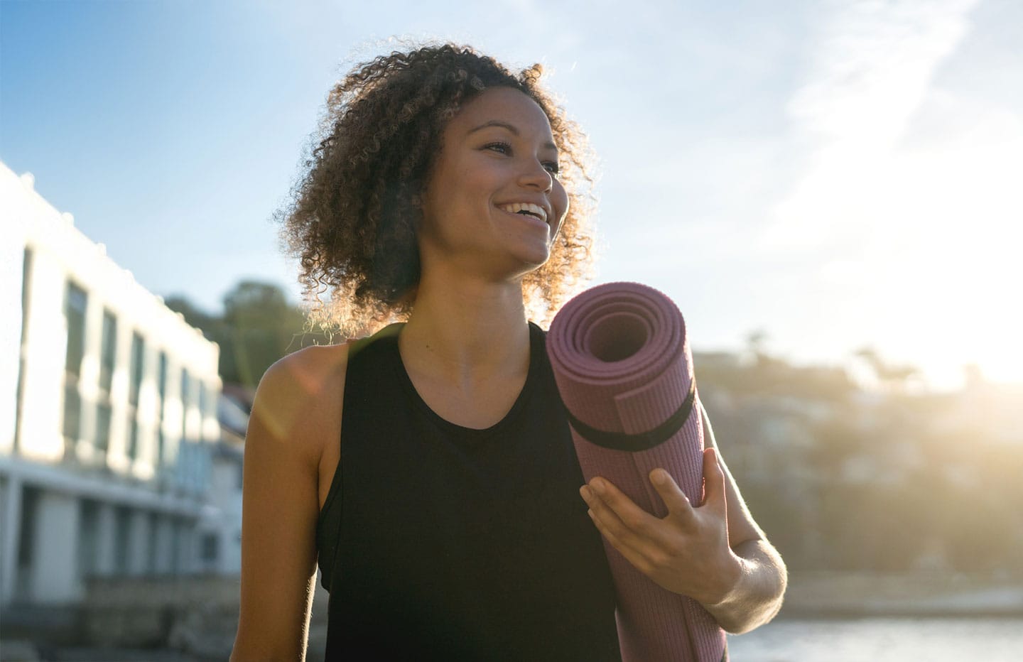 Woman smiling holding yoga mat