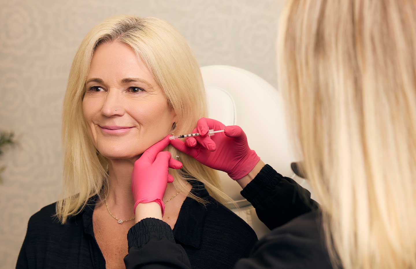Female health care provider injecting botox into clients chin